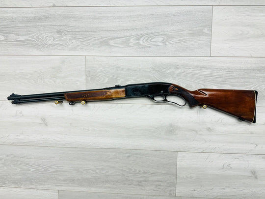 Classic wooden stock shotgun with ornate grip, ideal for hunting or collection, displayed on light wood floor.