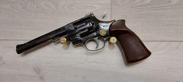 Vintage revolver with wooden grip and brass cartridges, ideal for collectors and shooting sports.