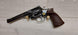 Vintage revolver with wooden grip and brass cartridges, ideal for collectors and shooting sports.
