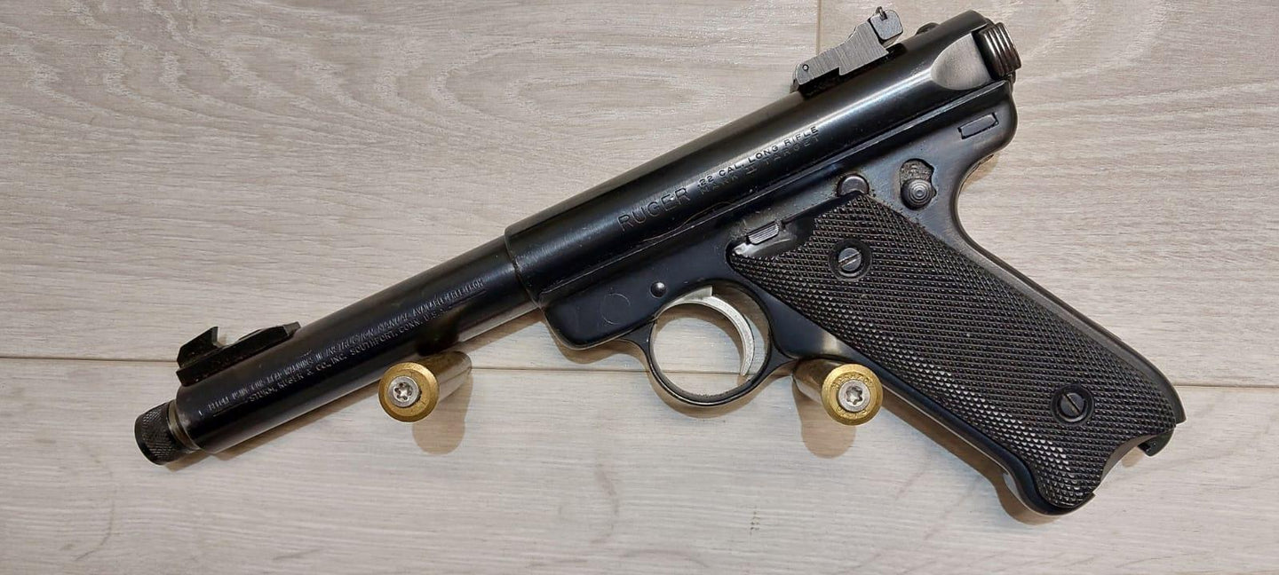 Ruger .22 Cal Long Rifle pistol with textured grip, displayed on wood surface with two cartridges