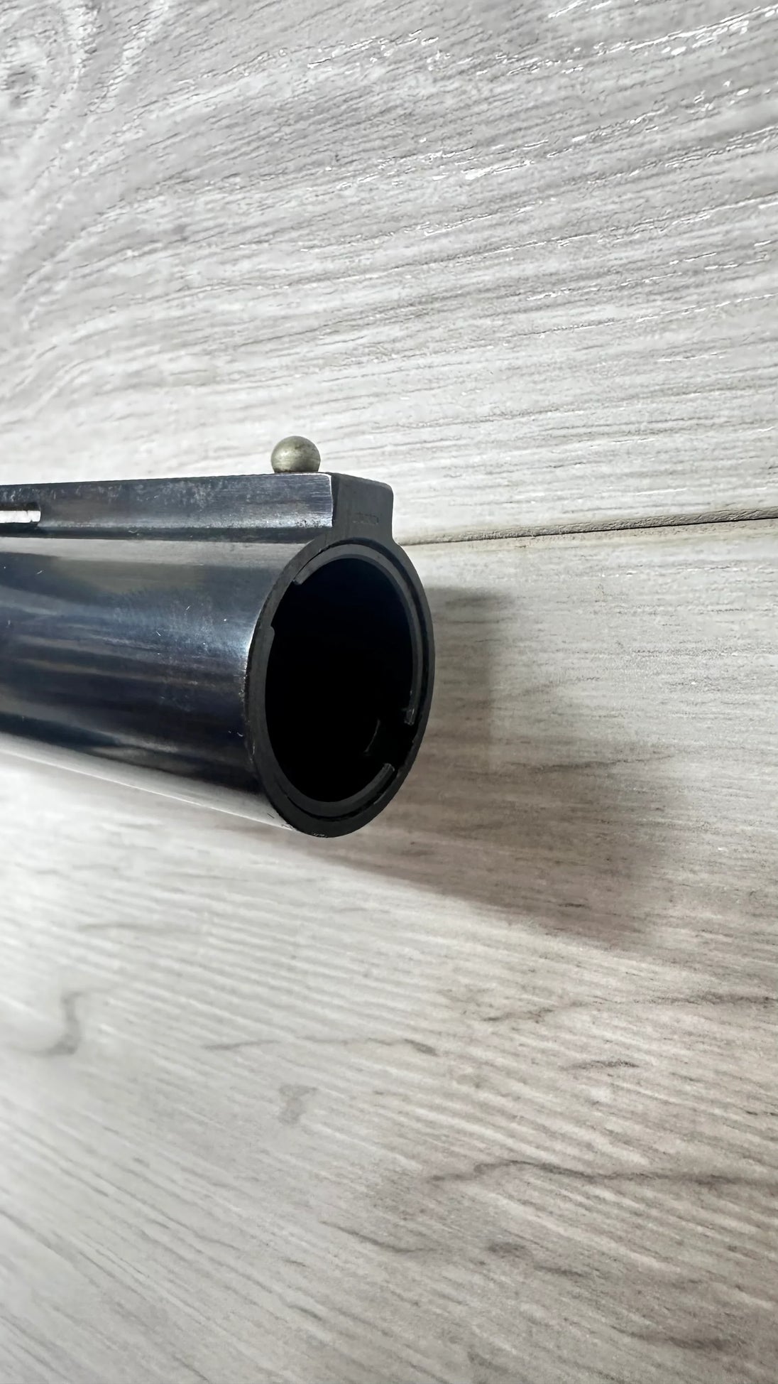 Close-up of shotgun barrel with front sight, ideal for hunting or competitive shooting.