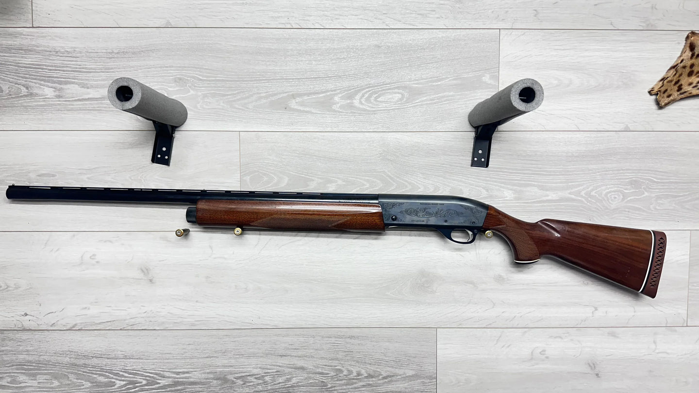 Mossberg Model 1000 shotgun with wood stock, displayed on light wood floor with foam barrel supports