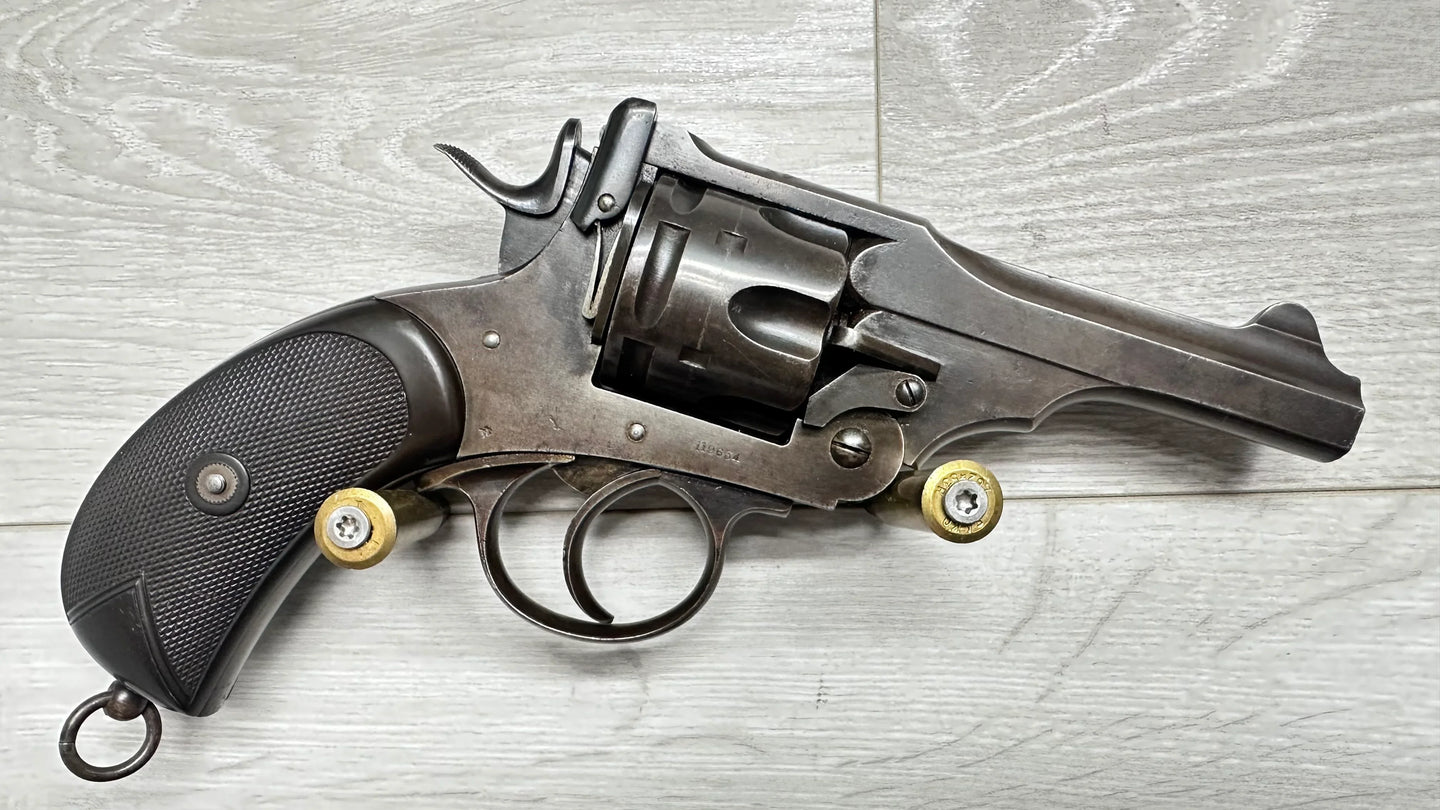 Vintage revolver with textured grip and brass cartridges, displayed on wood surface for collectors