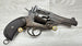 Vintage revolver with textured grip and brass cartridges, displayed on wood surface for collectors