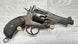 Vintage revolver with textured grip and brass cartridges, displayed on wood surface for collectors
