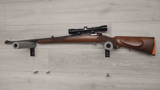 Wooden stock rifle with scope mounted on wall, ideal for hunting or sport shooting
