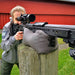 Shooter aiming precision rifle with scope, using Ulvhednar shooting bag on wooden post outdoors