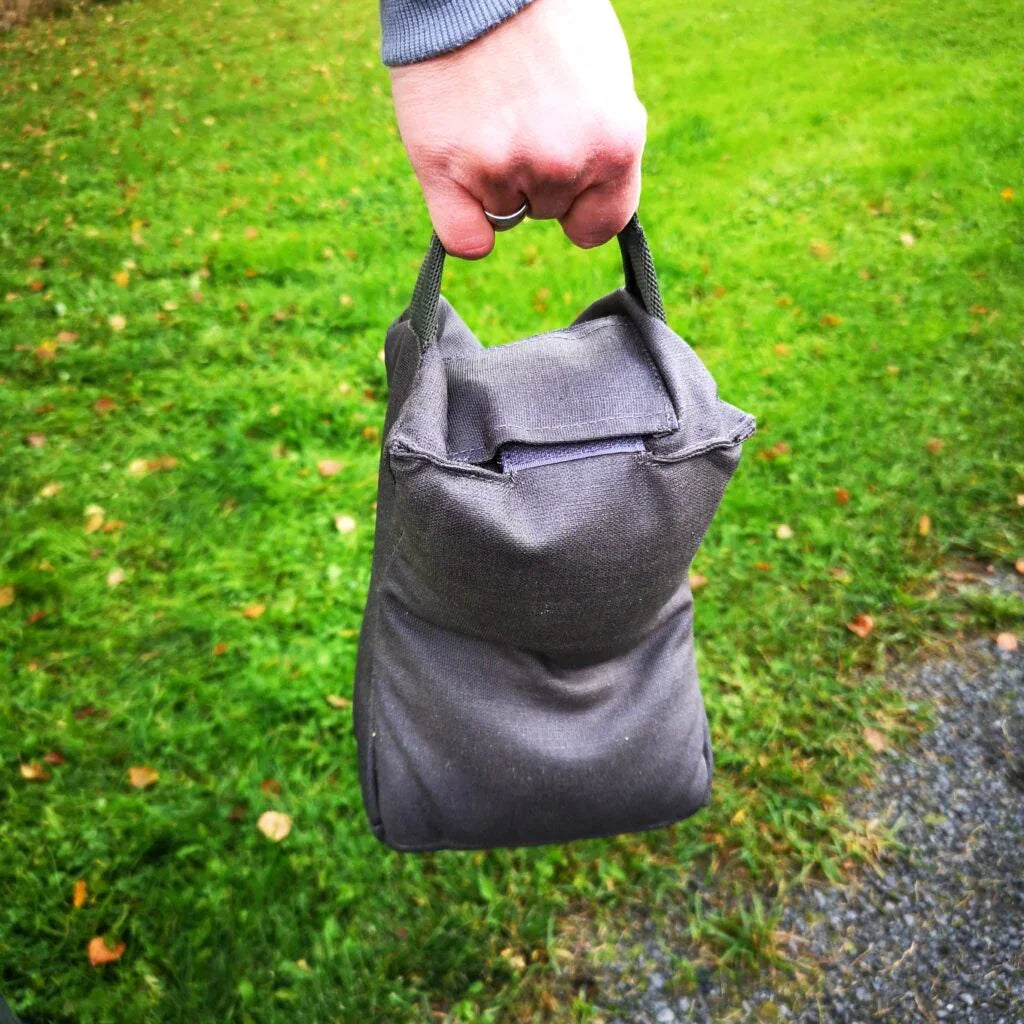 Hand holding gray canvas ammo pouch for shooting sports and hunting gear storage