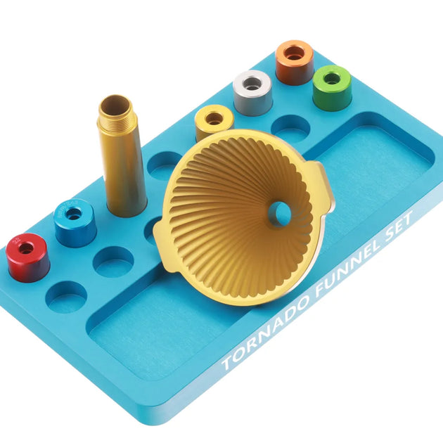 Precision brass annealing machine with gold-colored tornado funnel and various inserts on blue base