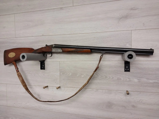 Classic over-under shotgun with wooden stock, mounted on wall with leather sling and shells
