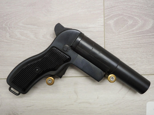 Black pistol with gold-tipped cartridges on light wood surface, ideal for collectors and sport shooting.