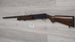 Used hunting shotgun with wooden stock displayed on wall, ideal for sport shooting and collection
