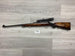 Wooden stock rifle with scope for hunting or sport shooting, displayed on gray wood floor