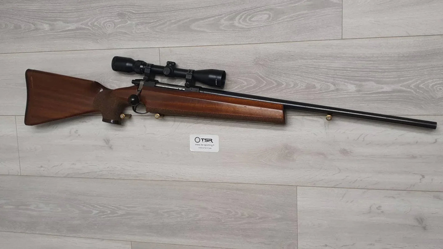 Wooden stock rifle with scope, ideal for hunting or sport shooting, displayed on light wood floor.