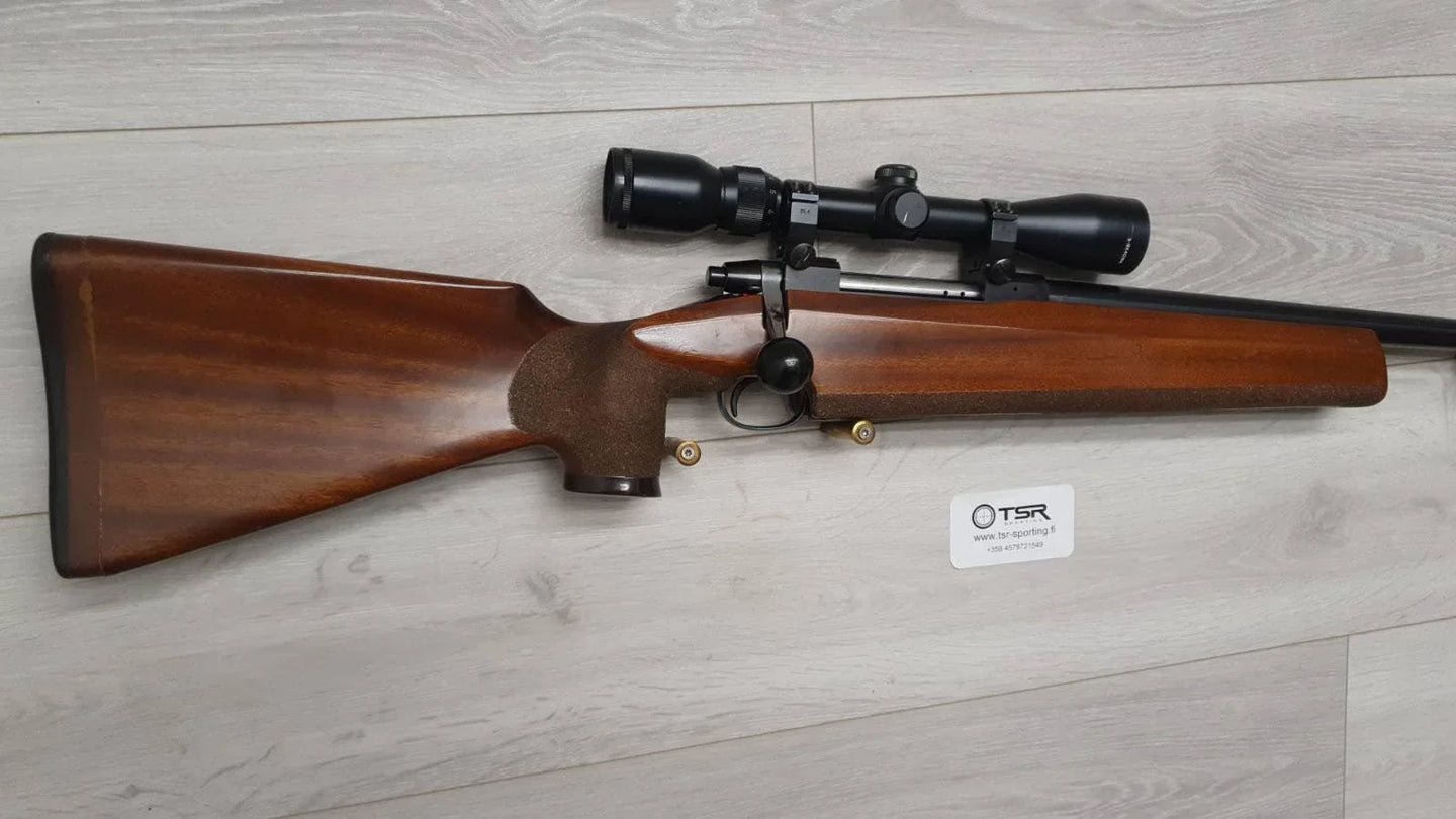 Wooden stock rifle with scope, ideal for hunting and target shooting, displayed on light wood floor.