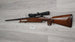 Wooden stock rifle with scope, ideal for hunting or sport shooting, displayed on wood floor.