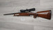 Wooden stock rifle with scope, ideal for hunting or sport shooting, displayed on wood floor.