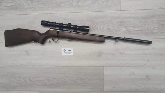 Bolt-action rifle with scope, ideal for hunting and target shooting, displayed on wood floor.