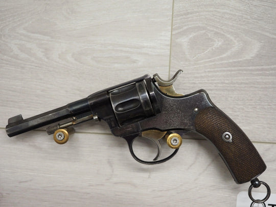 Vintage revolver with wooden grip and brass cartridges, displayed on light wood surface