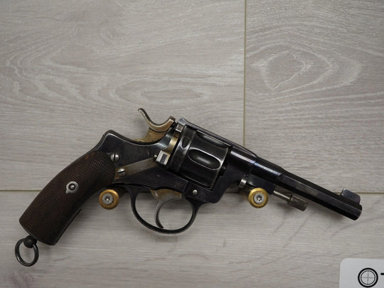 Vintage revolver with wooden grip and brass accents on light wood surface, ideal for collectors and enthusiasts.