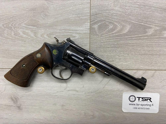 Used revolver with wooden grip for sport shooting or hunting, displayed on wood floor