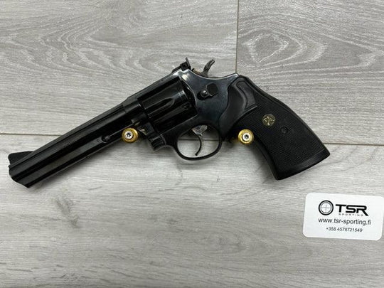 Black revolver with gold accents, ideal for sport shooting and hunting, displayed on wood-textured surface.