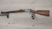 Vintage lever-action rifle with wooden stock displayed on wall mount, ideal for collectors and hunting enthusiasts.