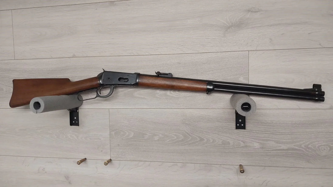 Classic lever-action rifle with wooden stock displayed on wall mount, ideal for hunting or collection.