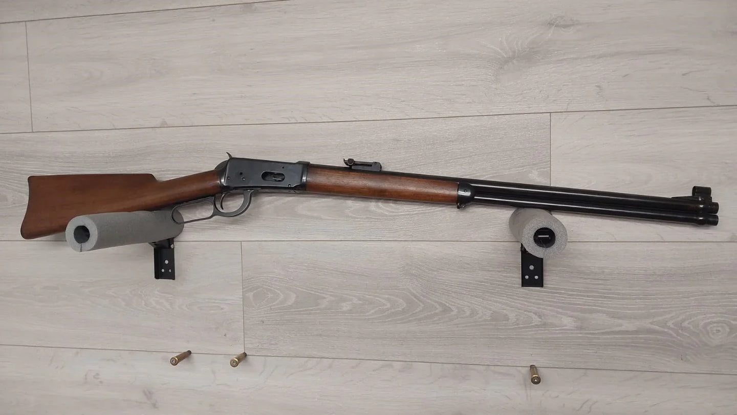 Classic lever-action rifle with wooden stock displayed on wall mount, ideal for hunting or collection.