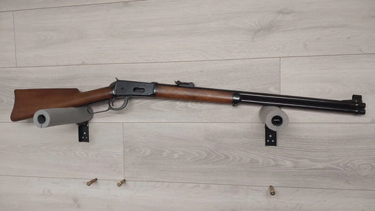 Classic lever-action rifle with wooden stock displayed on wall mount, ideal for hunting or collection.