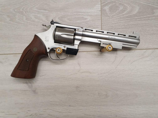 Taurus .357 Magnum revolver with wooden grip, stainless steel finish, and Rossi barrel, displayed on wood surface