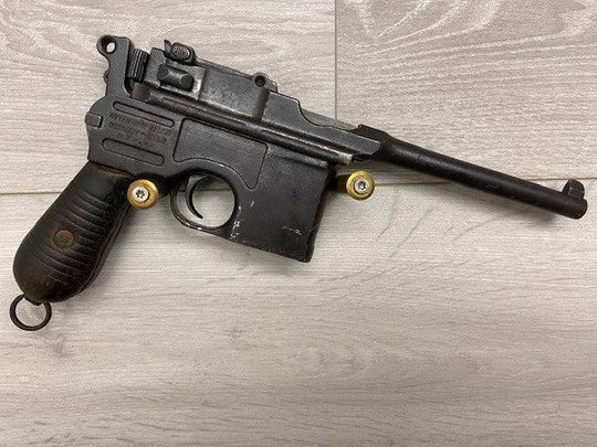 Vintage Mauser C96 pistol with wooden grip, displayed on light wood surface for collectors and militaria enthusiasts.